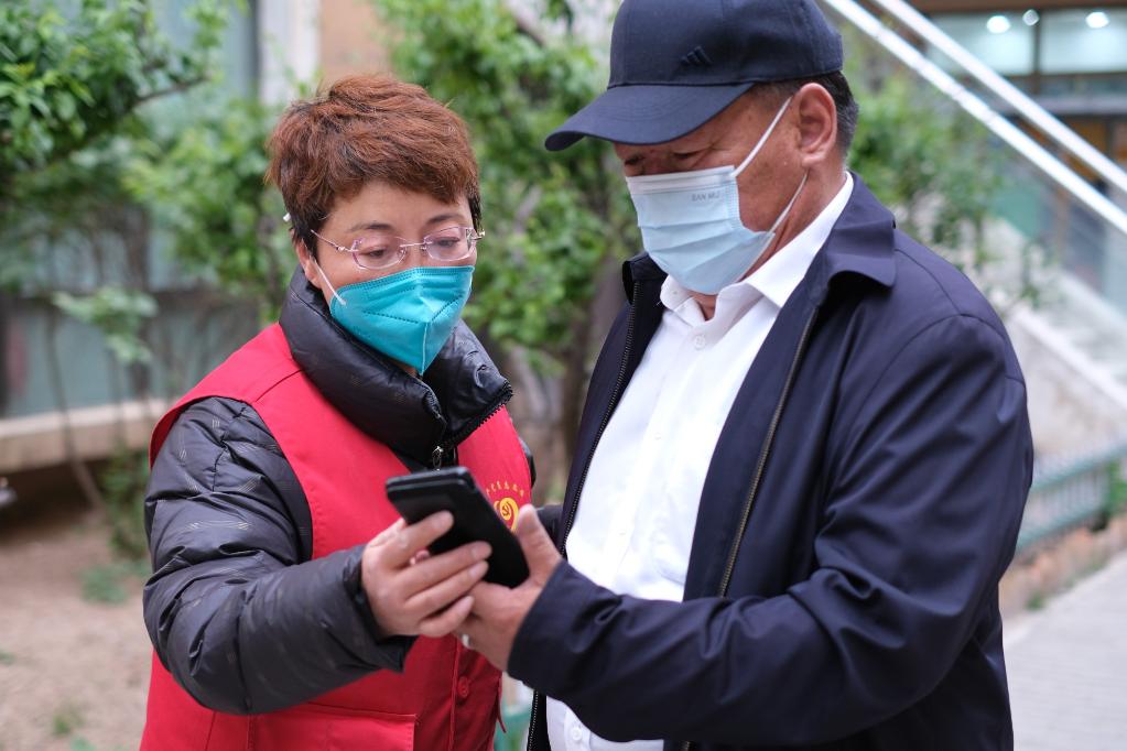 　　5月13日，张梅在西宁市城西区阳光华府小区核酸检测点查验居民的健康码和行程码。（新华社记者 童昊 摄）