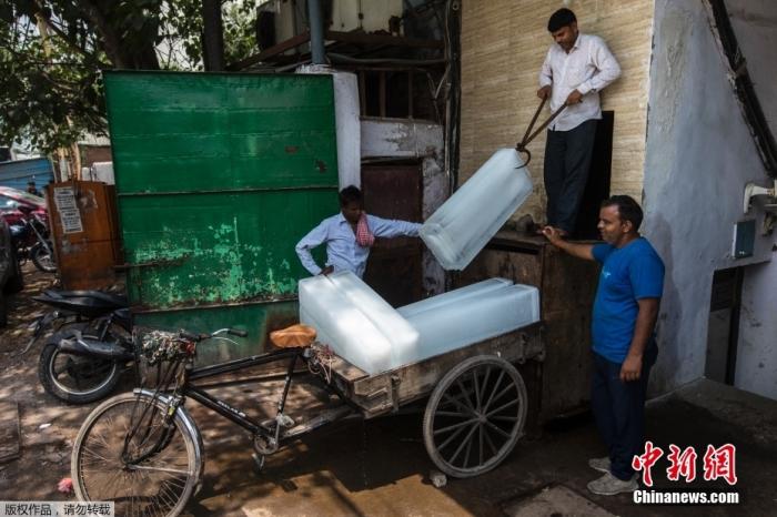 当地时间5月12日，印度新德里一家工厂的工人正在搬运冰砖用来解暑降温。
