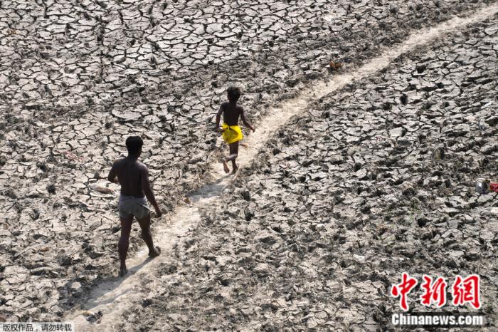 5月2日，印度新德里，一名男子和一名男孩走过几近干涸的亚穆纳河河床。
