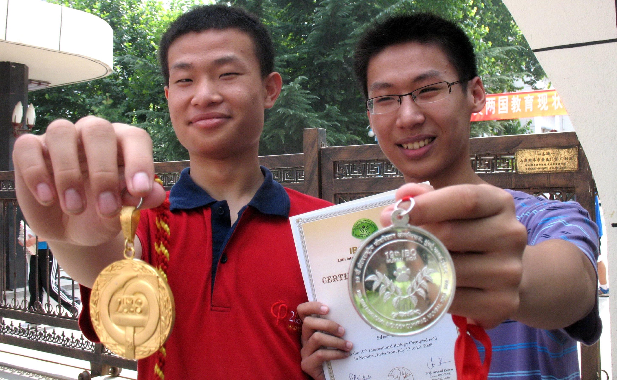 返回济南的该校中学生韦东奕(红衣者)和井淼向师生展示获得的金银牌