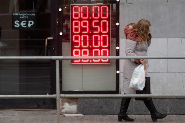2月24日，在俄罗斯首都莫斯科，一名女子经过一家外汇兑换点的汇率显示屏。新华社记者 白雪骐 摄