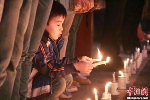 资料图：2013年04月20日08时02分，四川省雅安市芦山县发生7.0级地震。图为小男孩点燃蜡烛祈福。张一辰 摄