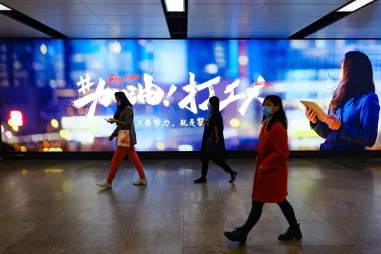 深圳,行人从地铁通道内“加油 打工人”主题广告前走过。 视觉中国供图