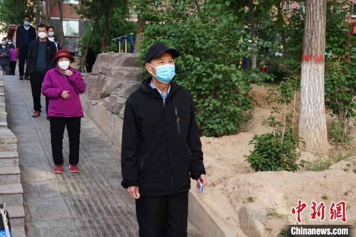 图为老人拿着便携式核酸检测采集码卡片排队。　马铭言 摄