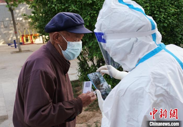 图为防疫人员用便携式核酸检测采集码卡片录入老人信息。　马铭言 摄
