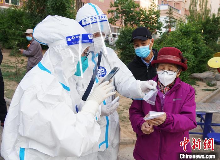 图为防疫人员为老人演示便携式核酸检测采集码卡片使用方法。　马铭言 摄