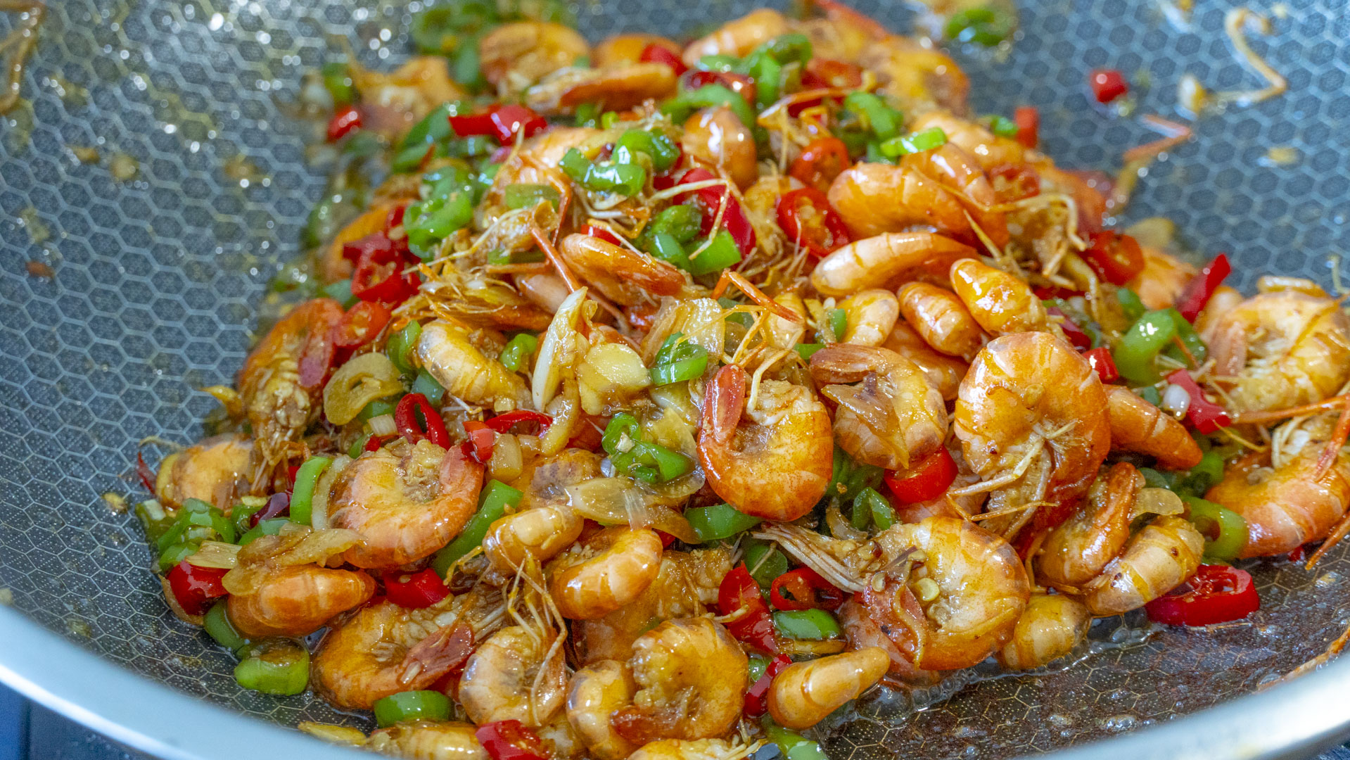 热下葱姜蒜爆香,然后把青红椒倒进来一起炒,辣椒炒至断生后倒入小河虾