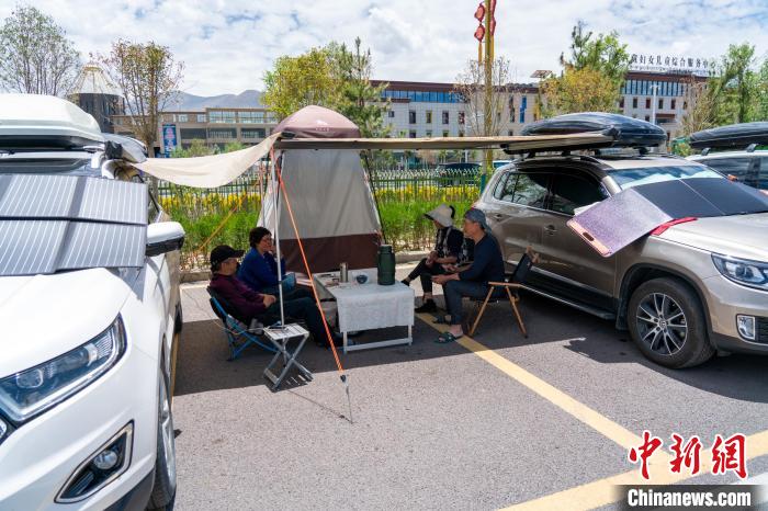 5月25日，拉萨市中华文化公园停车场内“房车族”在遮阳棚下休息，车辆前方太阳能电池板正在充电。 江飞波 摄