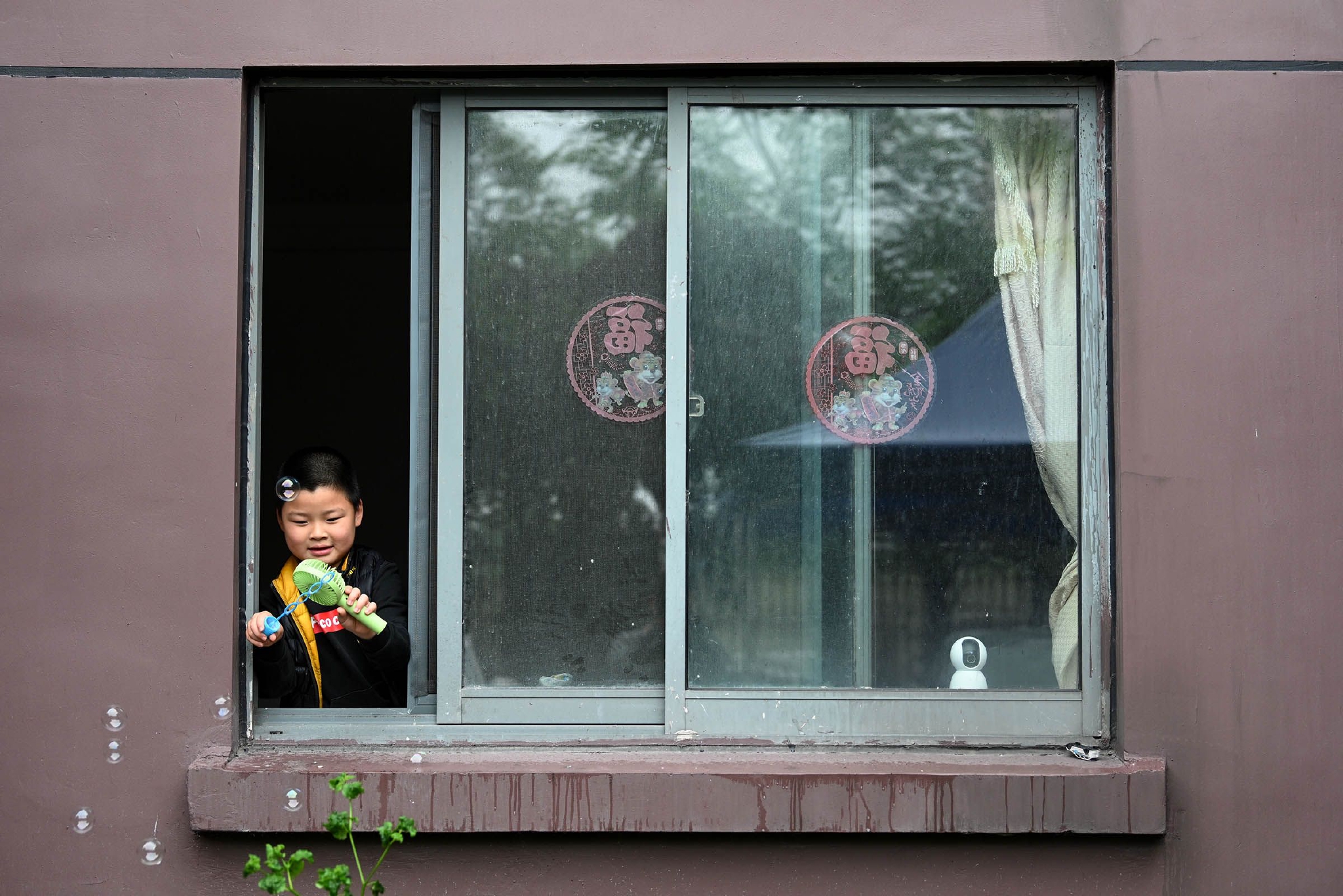 2022年5月13日,上海,闵行某小区,雨天,窗口玩泡泡的小男孩.朱伟辉 图