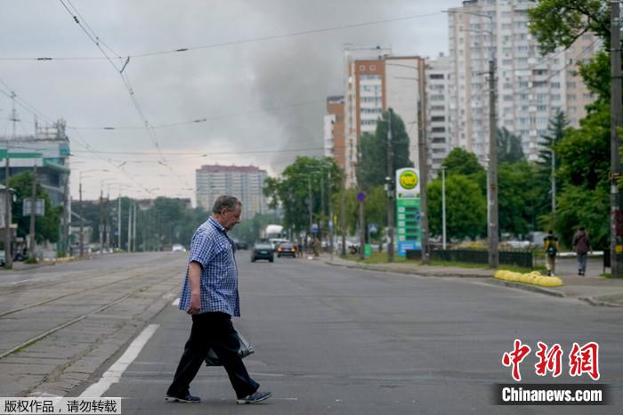 2022年6月5日，乌克兰基辅，一名男子穿过街道，烟雾在背景中升起。