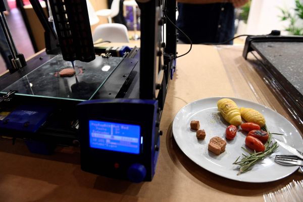 去年6月，西班牙巴塞罗那，世界移动通信大会上展示的3D打印机及其用植物蛋白打印的“人造牛肉”。（视觉中国）
