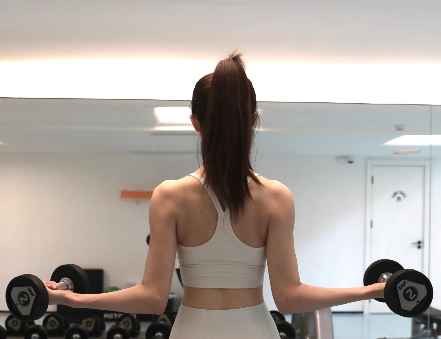 胡丹丹穿着白色的露脐胸衣,可以看到结实的腹肌;下半身也是白色的健身