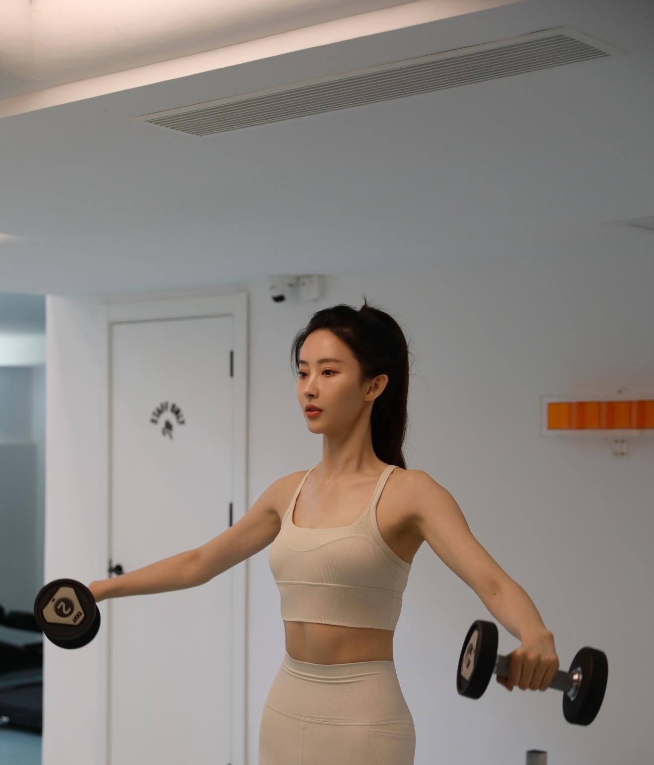 胡丹丹穿着白色的露脐胸衣,可以看到结实的腹肌;下半身也是白色的健身