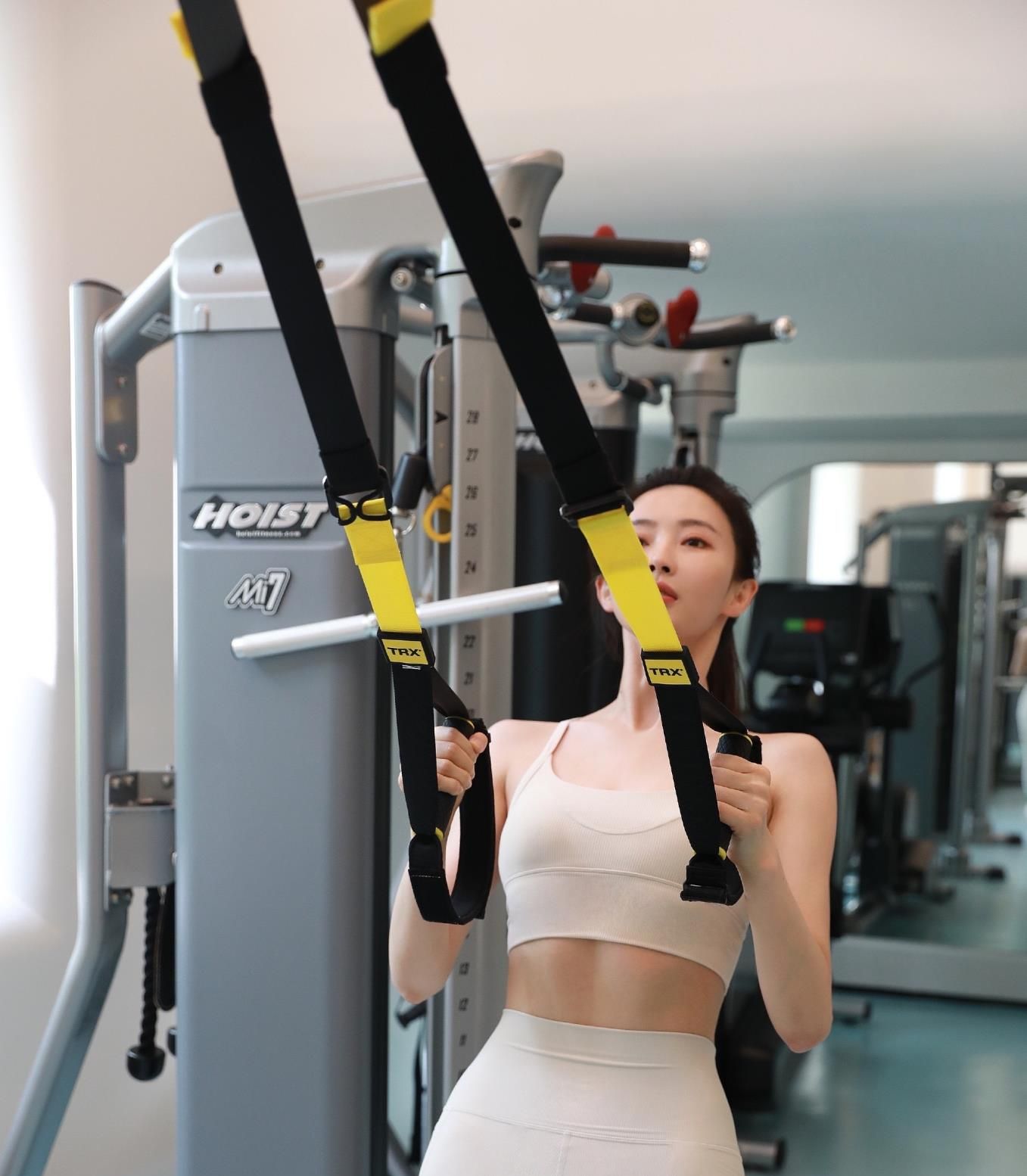 胡丹丹穿着白色的露脐胸衣,可以看到结实的腹肌;下半身也是白色的健身