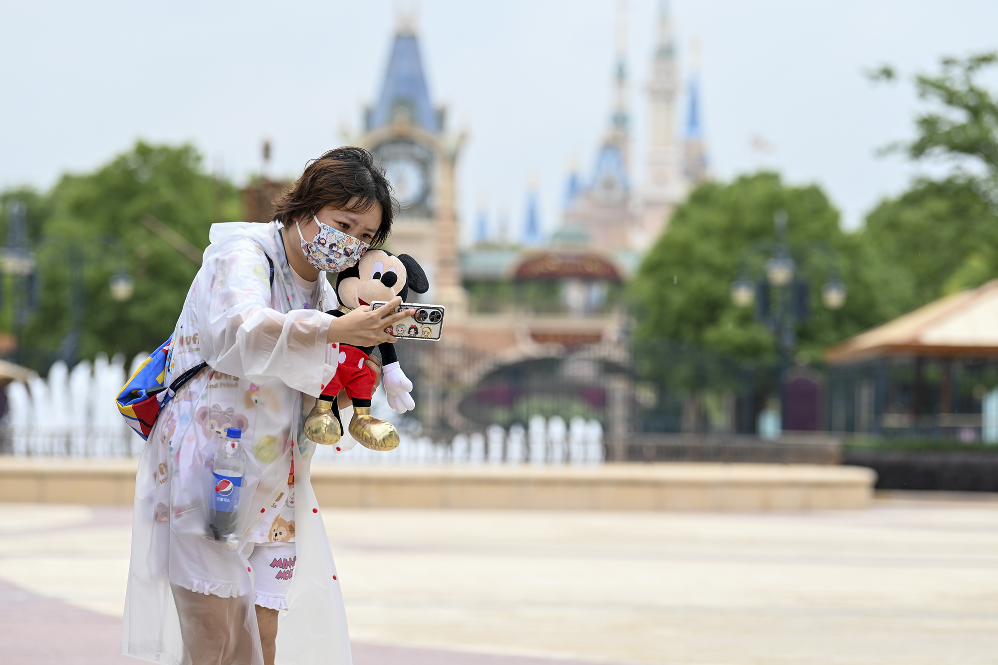 2022年6月10日,上海迪士尼,游客拿着米奇在城堡前自拍.