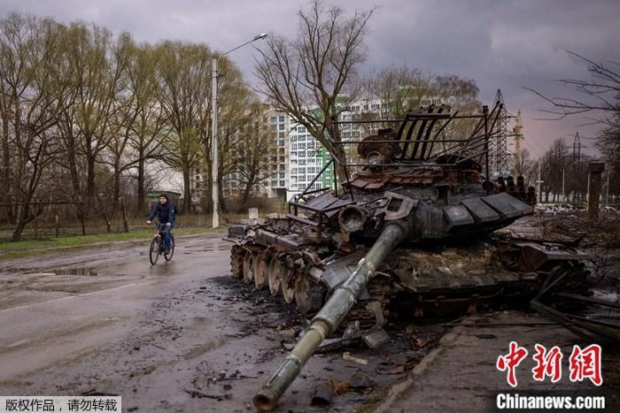 当地时间4月21日，乌克兰切尔尼夫，一名男子在一辆被毁的坦克旁骑车。
