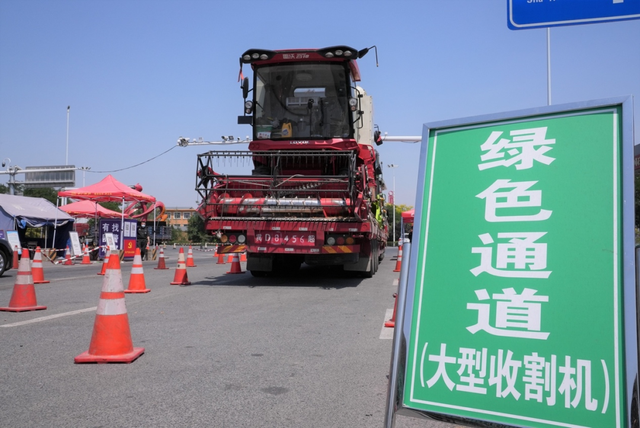 载着农机的货车正通过大型收割机绿色通道下高速