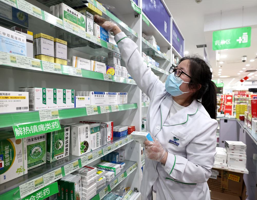 4月10日,上海国大药房南京西路店员工梁婷婷在店内为顾客挑选药品。(新华社记者 陈建力 摄)