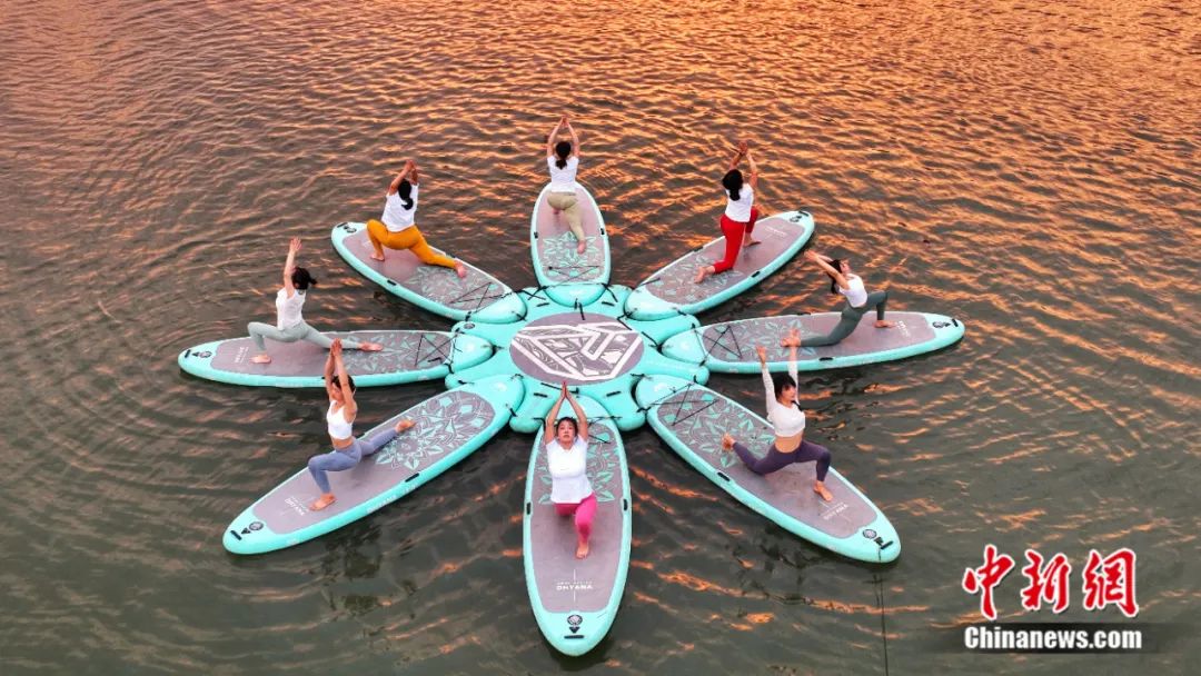 瑜伽爱好者在浙江湖州凤栖湖练习水上桨板瑜伽.中新社发 谢尚国 摄