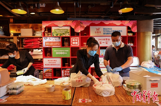 6月6日，北京市东城区一家餐厅内，店员在打包外卖。当日，除丰台区全域及昌平区部分区域外，北京全市其他地区餐饮经营单位开放堂食服务。根据防疫要求，各餐饮经营单位需控制人流密度，合理保持就餐间距，提倡隔位就座、打包外卖、使用移动支付等无接触方式结算。中青报·中青网记者 曲俊燕/摄