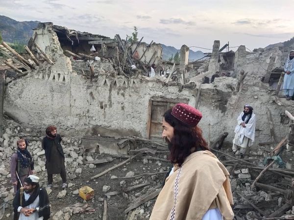 阿富汗民众站在废墟前。（视觉中国）