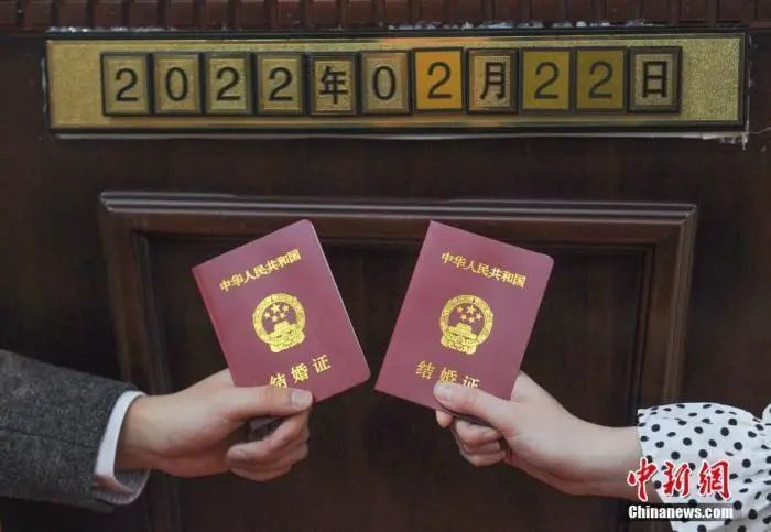 资料图:一对新人拿结婚证和日期数字拍照。中新社记者 王刚 摄