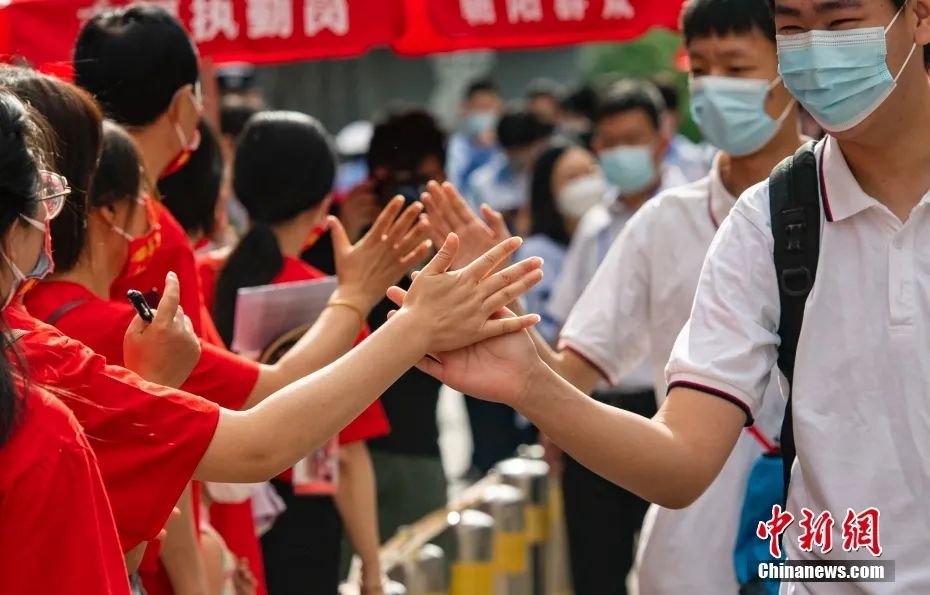 6月7日上午，北京市朝阳区陈经纶中学考点外，参加高考的学生入场前与送考老师击掌。中新社记者 侯宇 摄