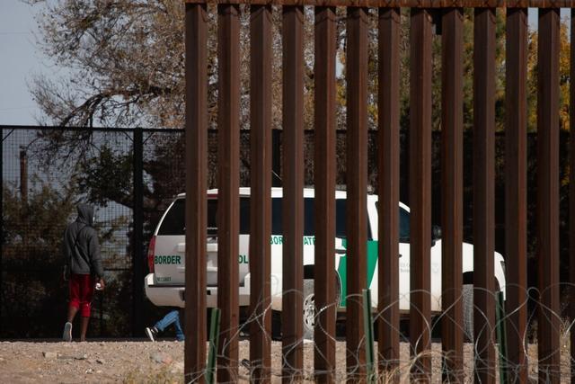 ▲试图翻越边境墙进入美国的移民被美国边境执法人员拦截。