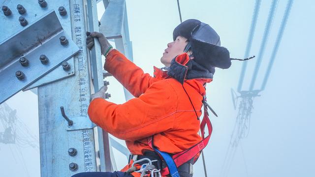 来自国网四川电力送变电建设有限公司的电力工人曾坤银正在雾中登塔进行高空作业。卢忠东摄
