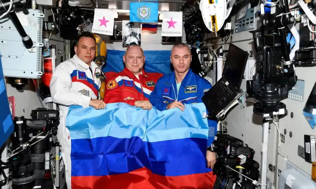 从配图中可以看到，3名身处国际空间站的俄罗斯宇航员微笑着拿着代表卢甘斯克的旗帜
