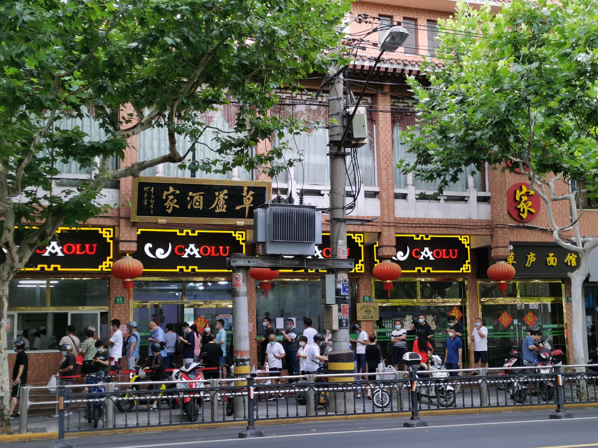 草庐酒家门前排起了长队,市民正在等候取餐.