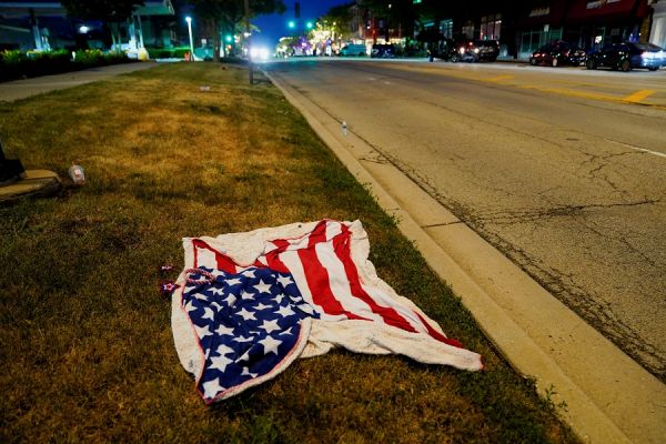 图片说明：4日，在美国海兰帕克市的独立日游行发生大规模枪击事件后，一面美国国旗被丢弃在游行道路上。（路透社）