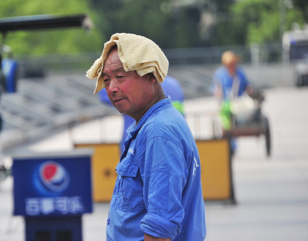 2022年7月13日,上海烈日当空,外滩市政养护工人头顶湿毛巾依然挥汗如