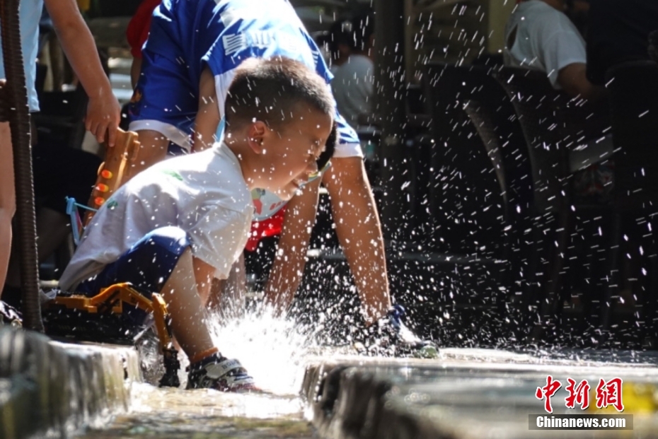 7月9日	 ，陕西咸阳，小朋友在一民俗村的小水渠旁玩水 。 中新社记者 张远 摄
