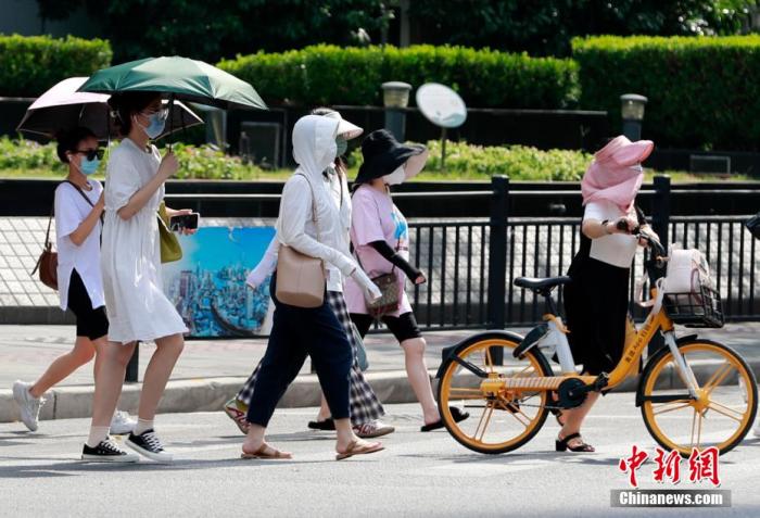 资料图：路人“各显神通”躲避炙热的阳光。 汤彦俊 摄