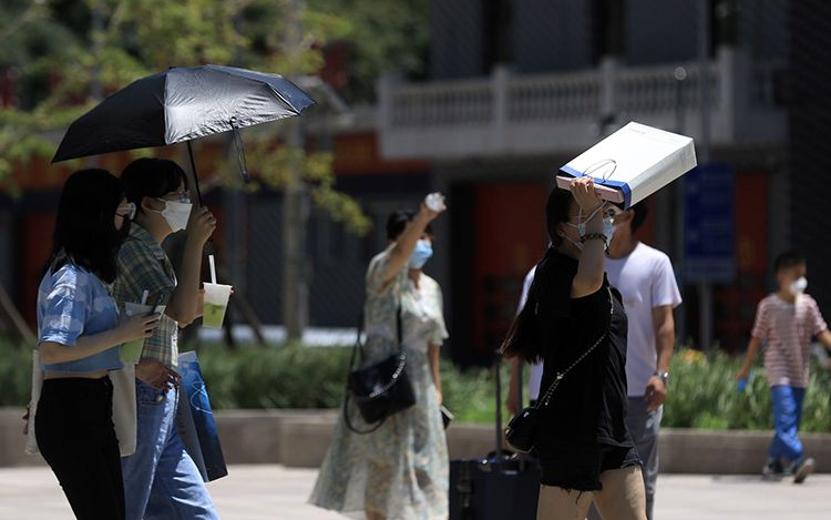 高温天气下,市民用纸袋遮挡刺眼的阳光.新京报记者 浦峰 摄
