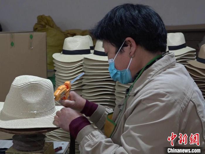 图为河北省大名县西付集乡草帽加工厂员工使用胶枪装饰草帽。　庞涛 摄