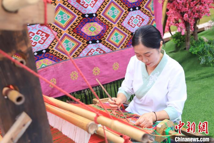 左翠平坐在斜织机前,脚踏提综,挥动挑刀,娴熟地喂线织锦. 马佳欣 摄