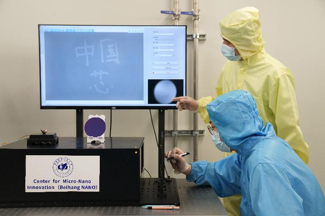 ▲2021年6月24日，北京航空航天大学集成电路学院科研人员（前）在5个原子层厚的纳米磁性薄膜上写下“中国芯”。图/新华社