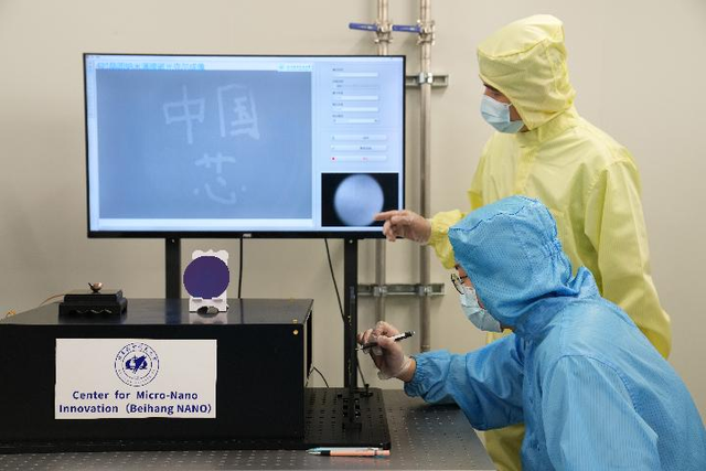 ▲2021年6月24日,北京航空航天大学集成电路学院科研人员(前)在5个原子层厚的纳米磁性薄膜上写下“中国芯”。图/新华社