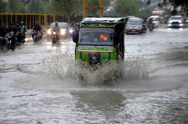 图说：7月25日，车辆涉水经过巴基斯坦卡拉奇一条被积水淹没的道路。新华社发