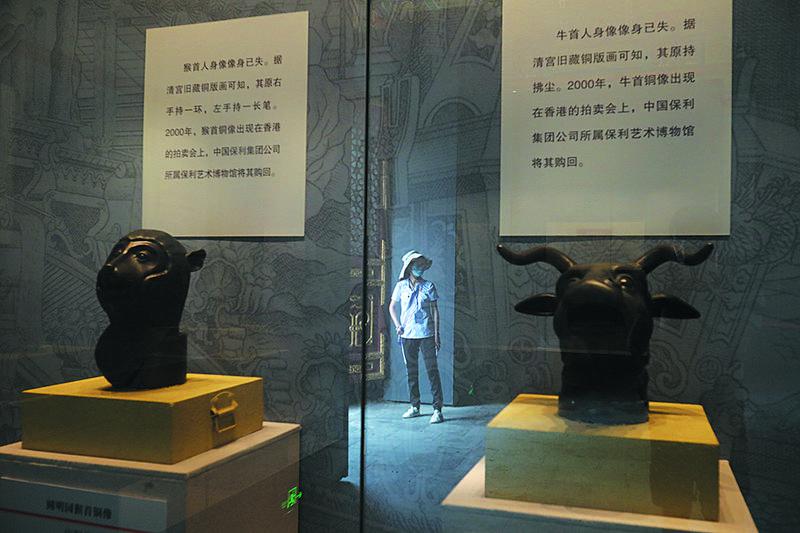 7月20日，正觉寺兽首仿制品展示柜玻璃上反射出一位女士的身影。新京报记者 王嘉宁 摄