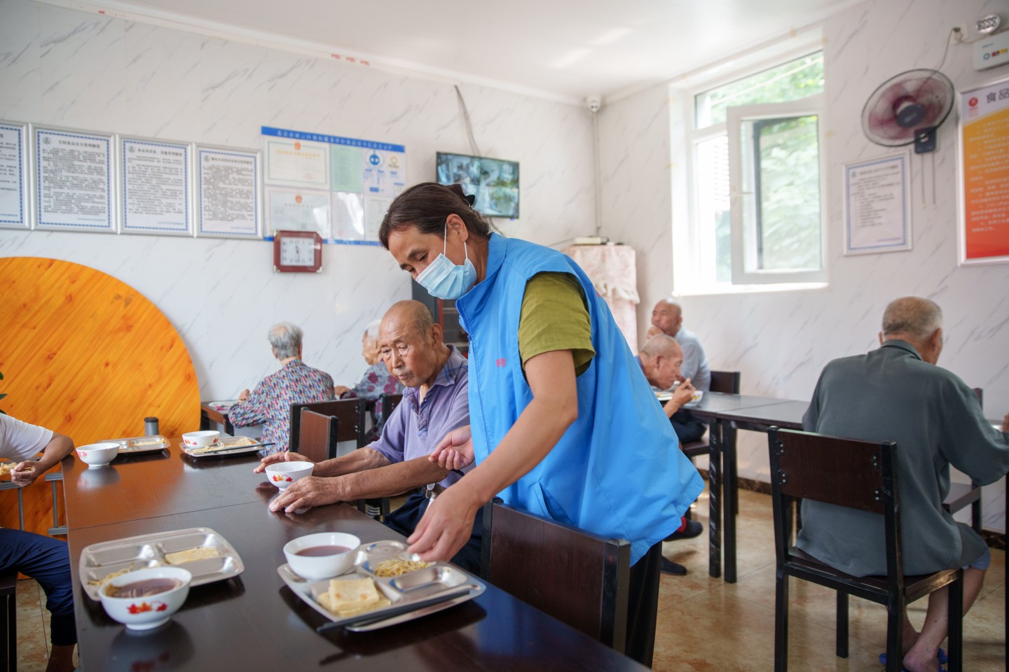 密云区河南寨镇河南寨村幸福晚年驿站，邻里互助员石桂芝收拾餐桌。新京报记者 王子诚 摄