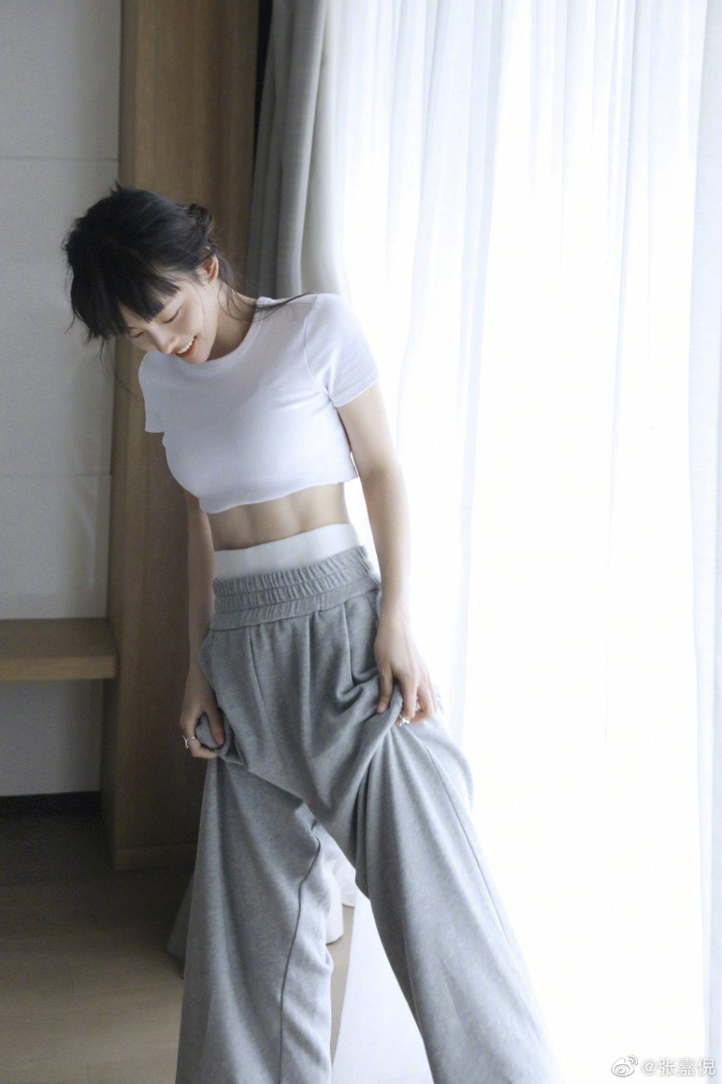第三张,是一张全身照.张嘉倪身穿白色短上衣,搭配灰色休闲长裤.