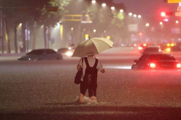 8日，韩国首尔江南区，一名男子在暴雨中涉水。（韩联社）