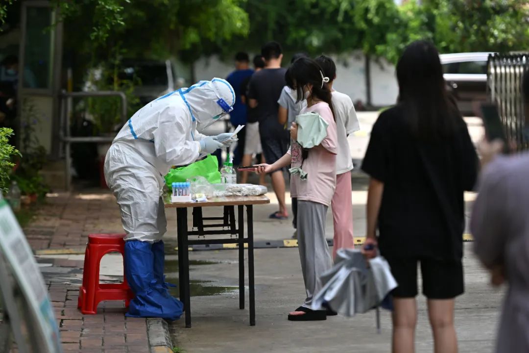 ▲滞留三亚的游客周世勋（左）在为社区居民采集核酸信息。新华社记者 郭程 摄