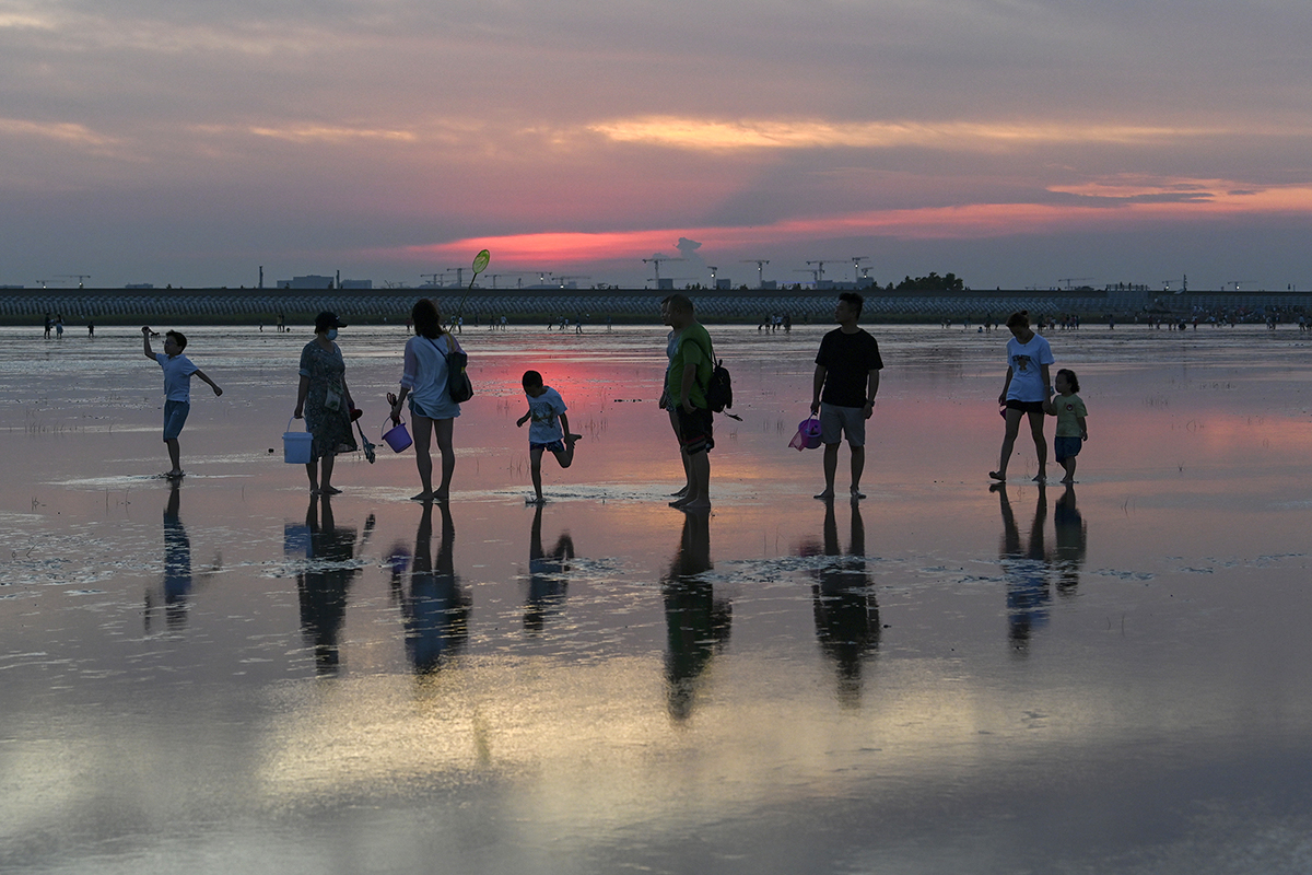 2022年8月14日,上海,东海,市民在滩涂上玩水消暑.