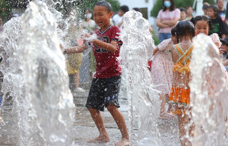8月12日，南京市小朋友在街头喷泉处戏水纳凉。