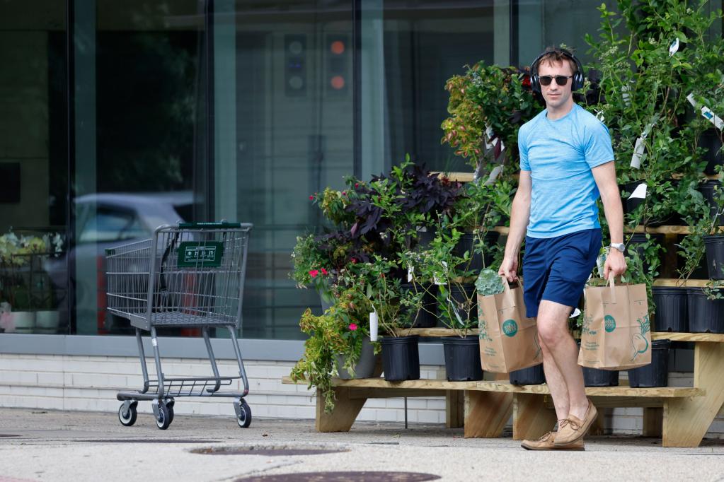 6月14日，在美国华盛顿，一名男子提着购物袋从一家食品超市旁走过。新华社发（沈霆摄）