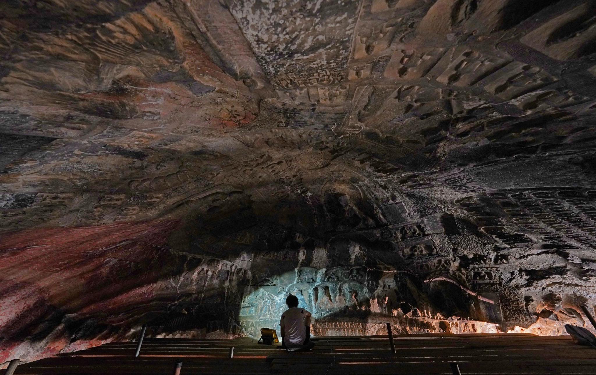 古阳洞内，考古人员在观察洞窟内的石刻艺术，并做登记和描述。